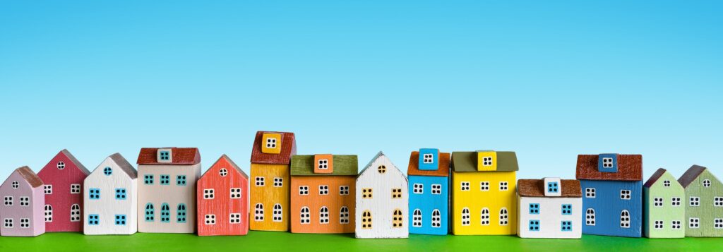 Colorful miniature houses arranged in a row on blue background. Urban city background banner.