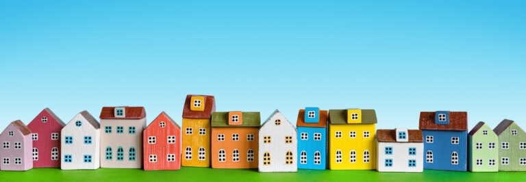 Colorful miniature houses arranged in a row on blue background. Urban city background banner.
